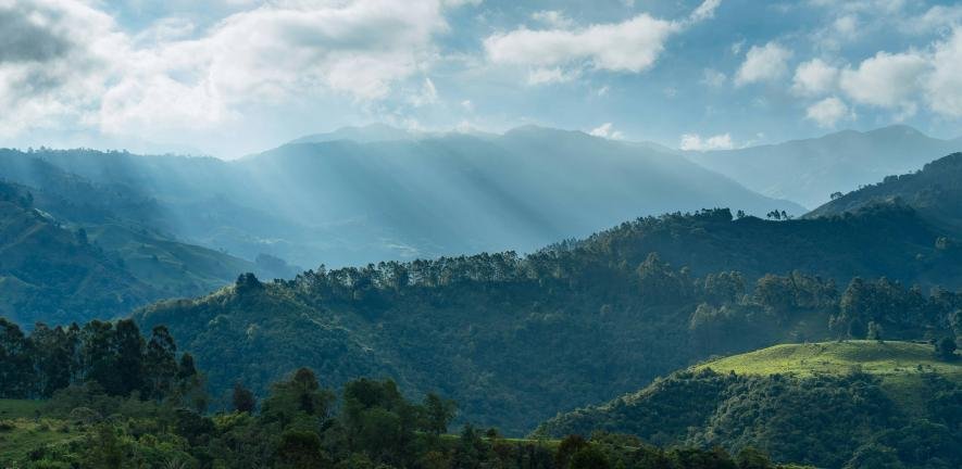 Photograph of sunlight poking through clouds onto mountains