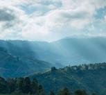 Photograph of sunlight poking through clouds onto mountains