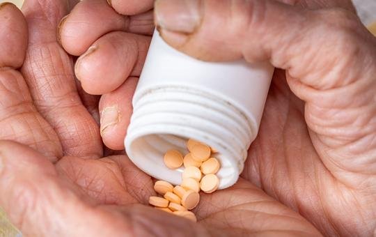 Elderly Woman's Hands and Orange Pills